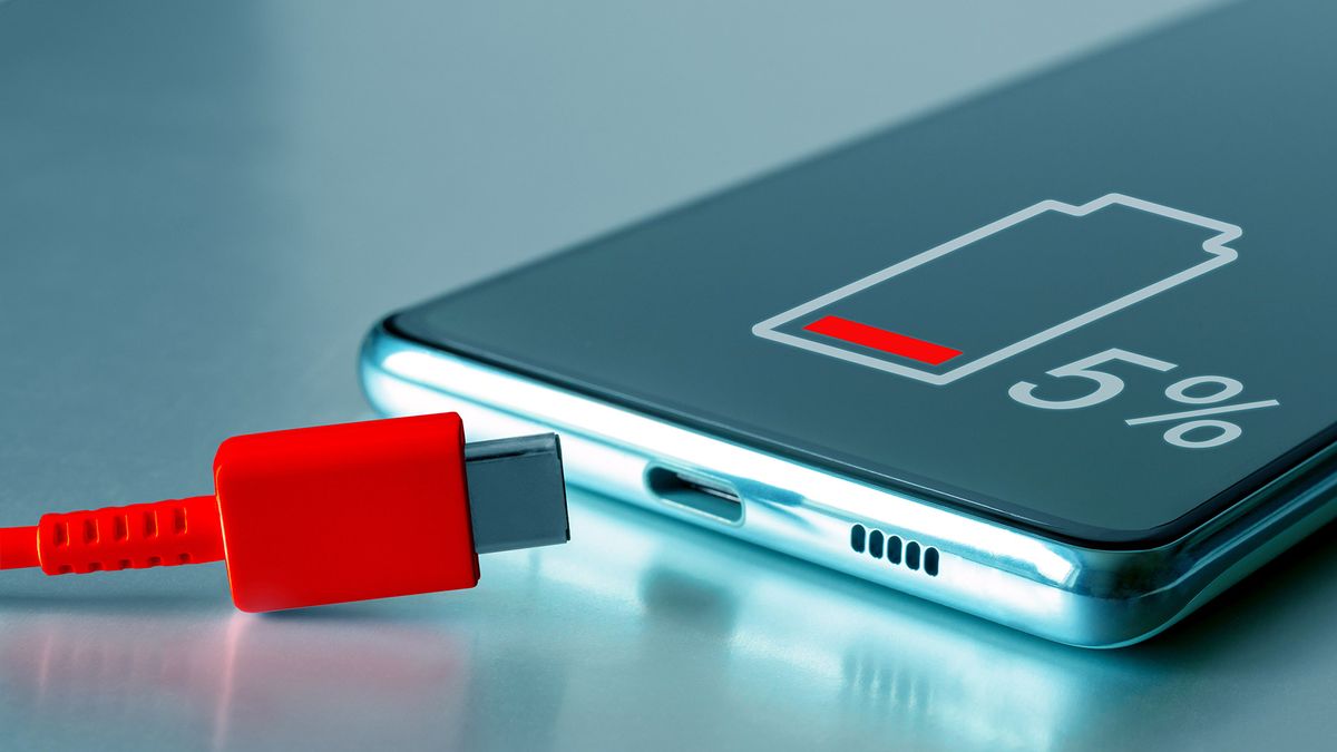 A phone displaying a &#039;5%&#039; battery icon, with a red USB-C cable near the charging port