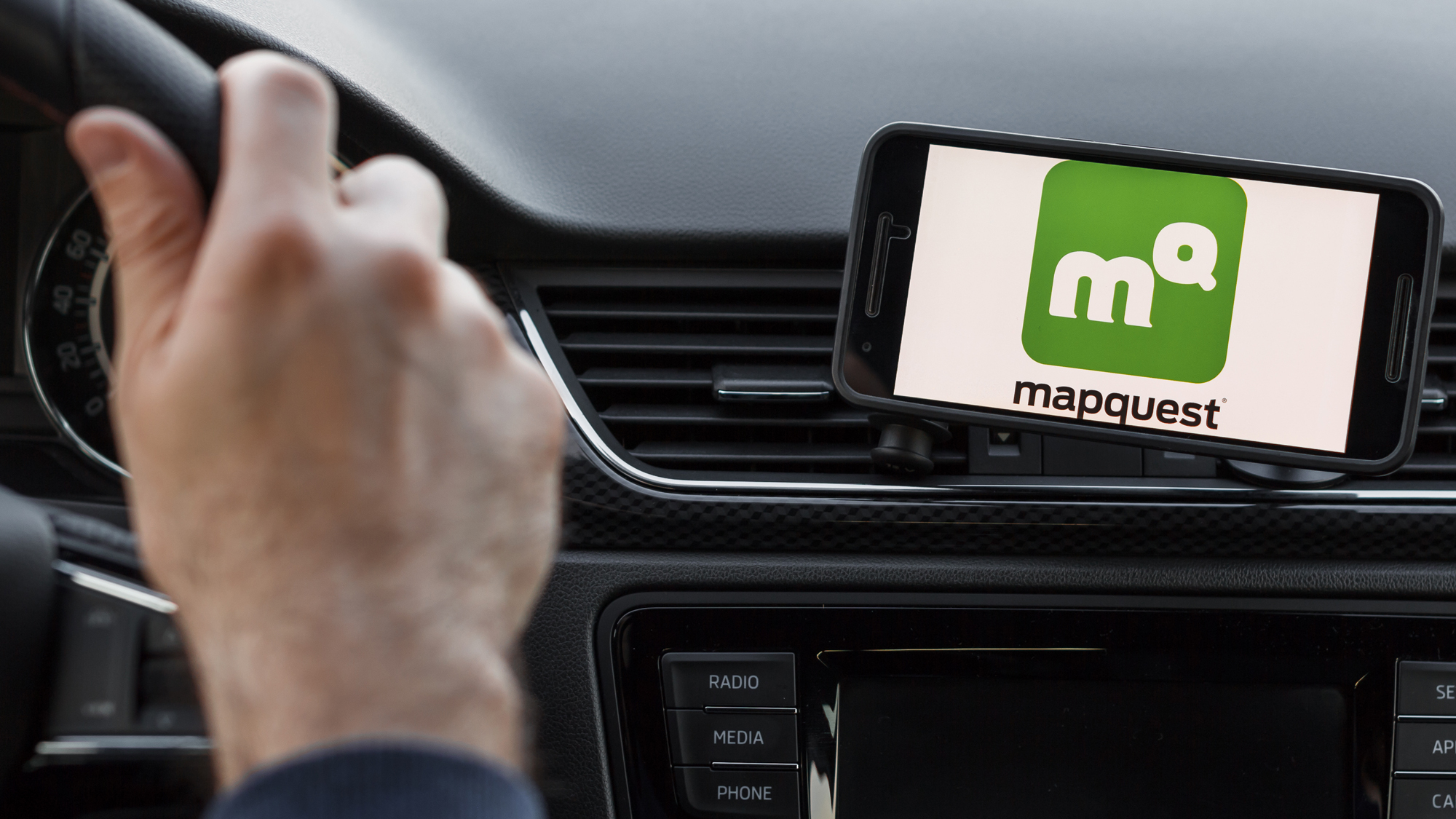 mapquest logo on an iphone strapped to a car dashboard