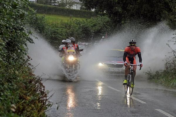 Race vehicles kick up a deluge of water behind Mathew Cronshaw (Node 4-Giordana)