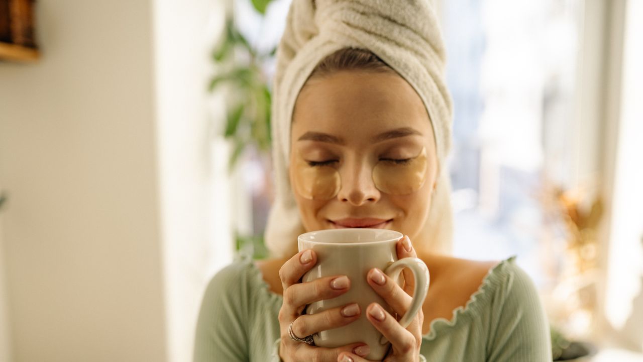 Woman wearing towel around her head and enjoying a hot drink