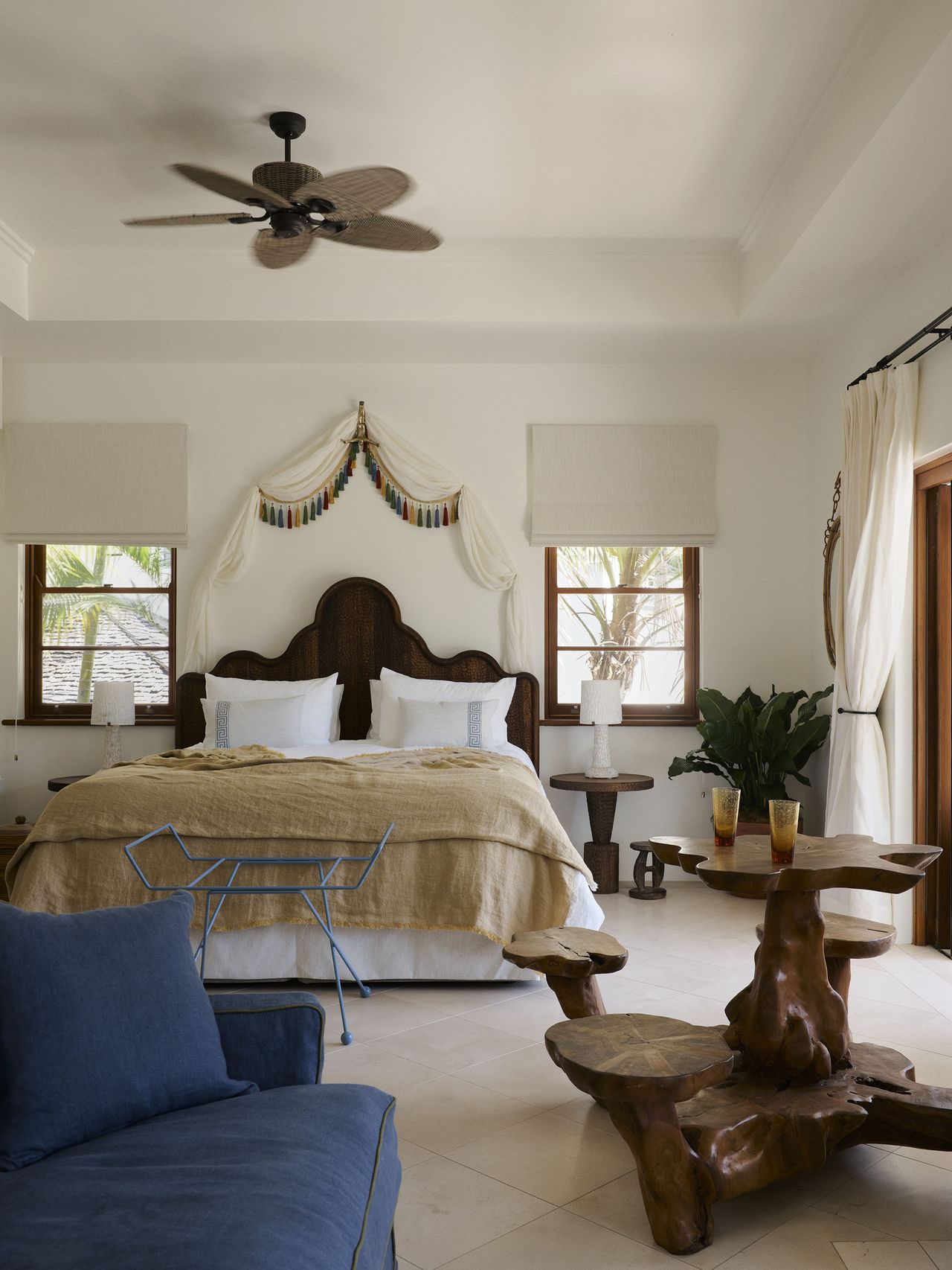 A bedroom in Raes Guesthouses with a colorful tassel bed canopy and blue sofa