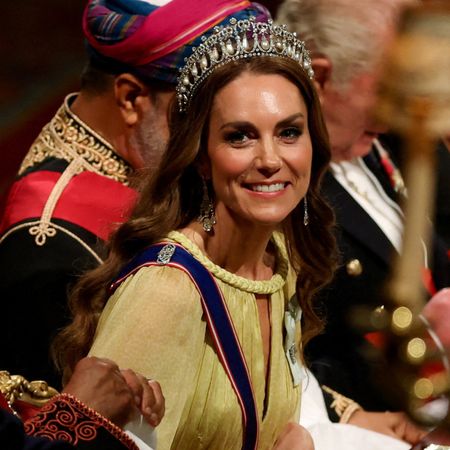 Princess Kate leaning forward in a yellow gown and tiara at a banquet table