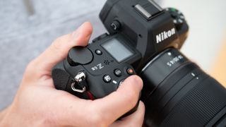 Close up of the logo on a Nikon Z6 III camera held in a pair of hands