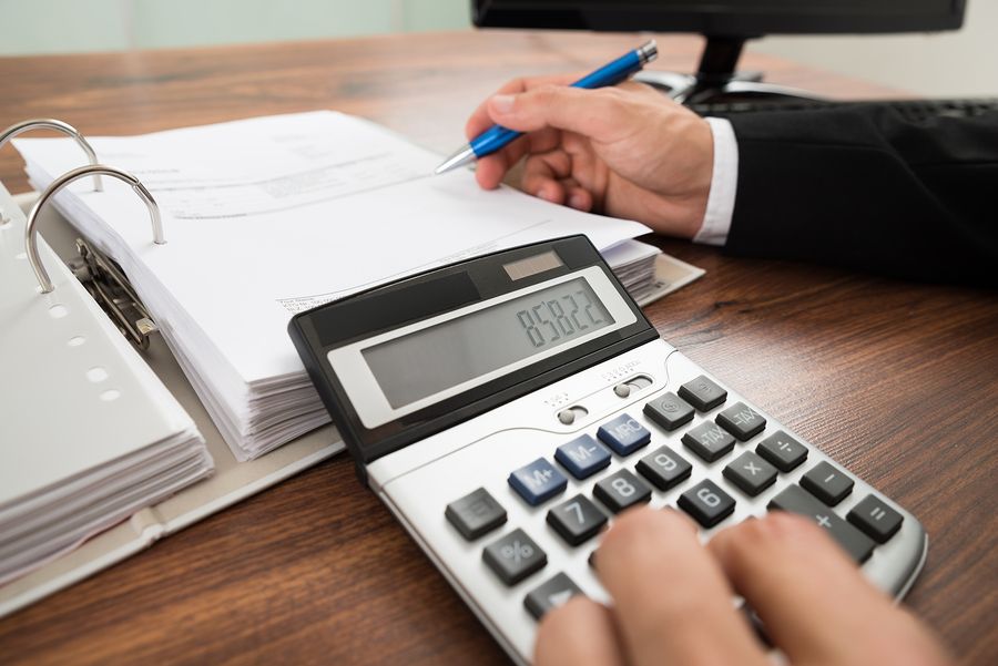 Man typying on calculator and writing on paper in file