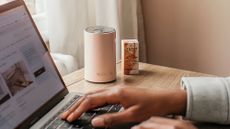 A NEOM diffuser in the background of someone working on a laptop