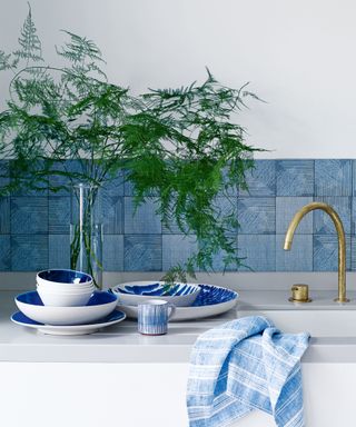 How to install a backsplash example, with blue tiles and dark grout in a white kitchen.