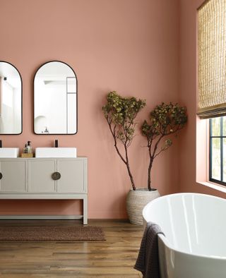 Red-pink bathroom with wood flooring and freestanding tub
