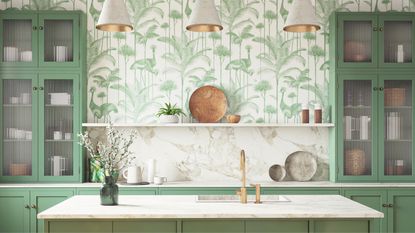 An example of pretty kitchen island pendant lighting ideas. This image shows three gray cone lights with bright golden interior installed above kitchen island with mint green and white leafy wallpaper, green cabinets, white marble surfaces and green base cabinets