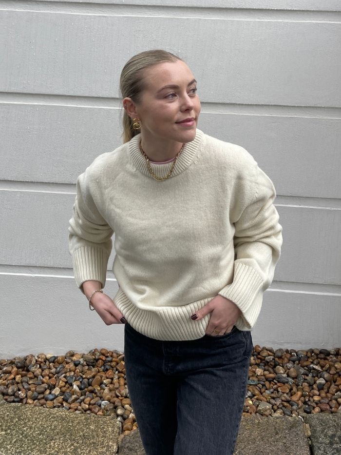 Woman wears cream jumper and black jeans