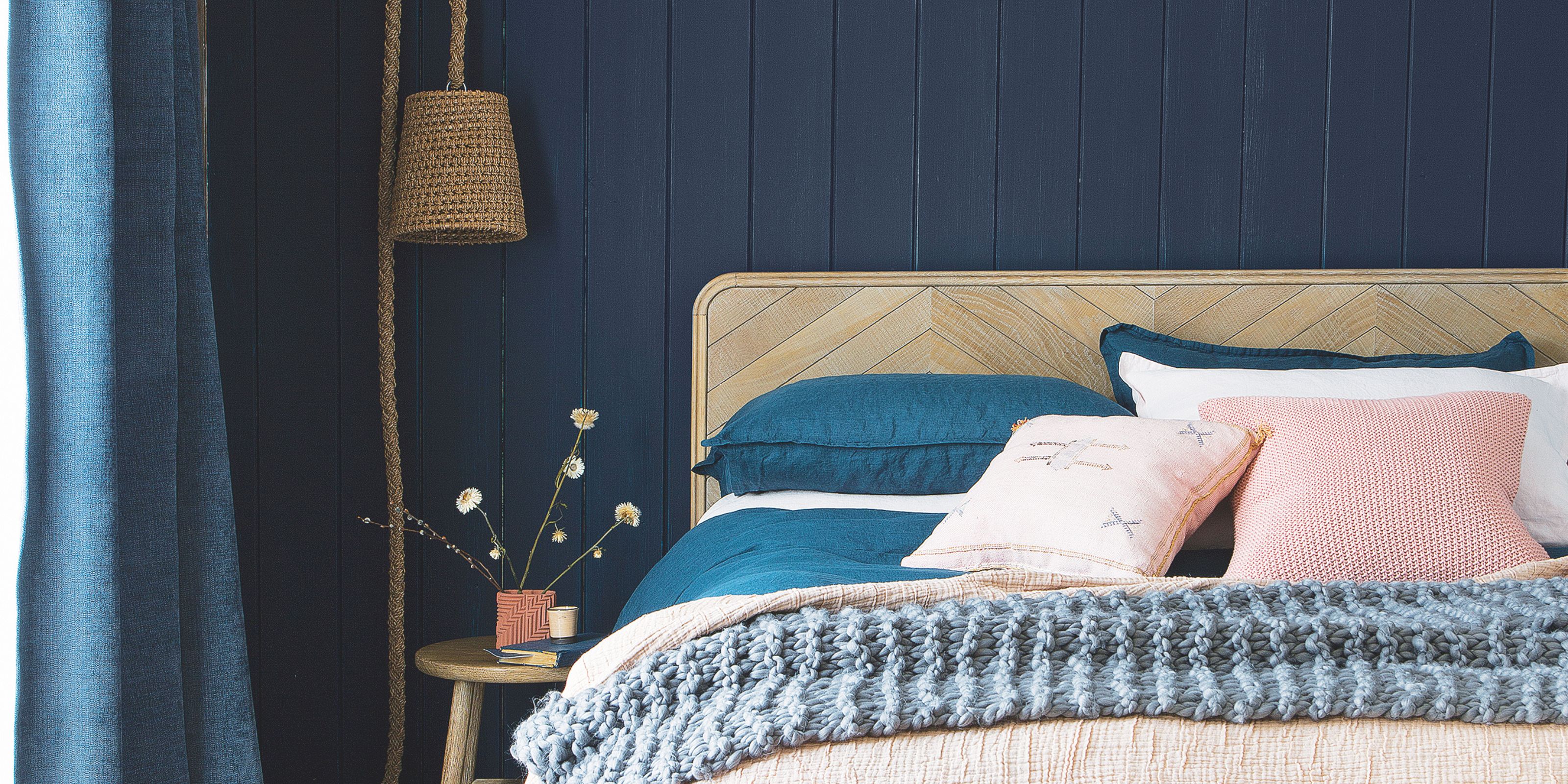 A dark blue bedroom with rattan and pink accents