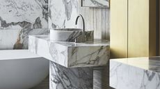 a marble bathroom vanity and basin with a brass cabinet