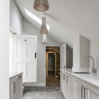 utility room with white wall and grey cabinets and ceiling light