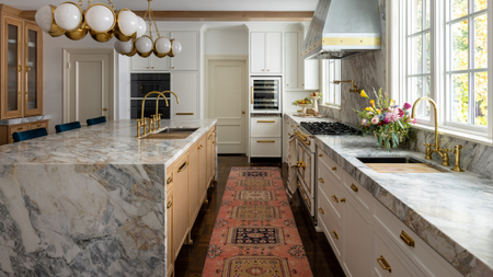 A kitchen with a long runner, and marble island