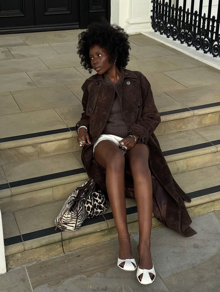 An image of @daniellejinadu wearing a brown suede trench coat with a chocolate coloured knit and lace trim satin shorts.