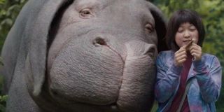 The giant elephant cuddles to a little girl in Okja