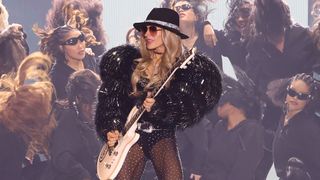 Orianthi wears sunglasses and a wide brimmed hat as she plays her white PRS signature guitar live at the Victoria's Secret Fashion Show 2024: a performance for which she used her Orange $219 practice amp.