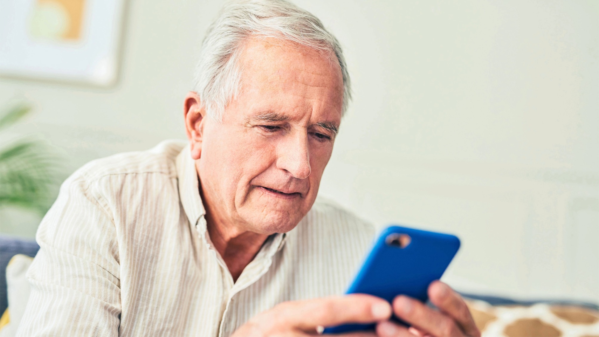 Close up of senior man using his cellphone while sitting at home