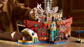 Someone places the final piece on the Lego The Baratie Floating Restaurant as it sits on a wooden table