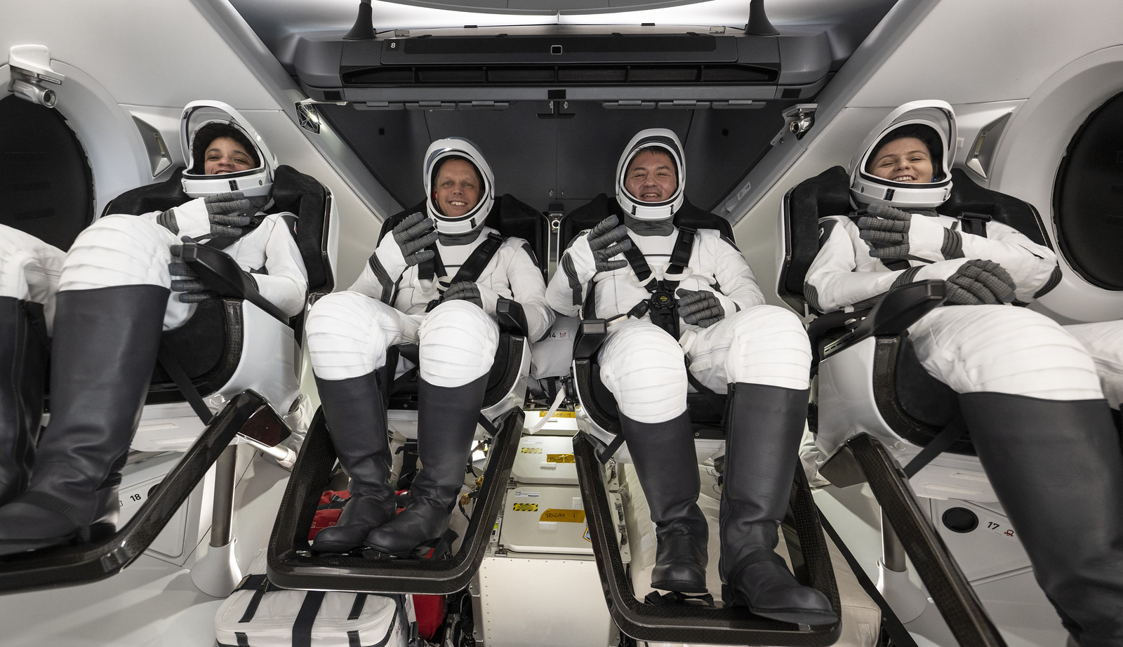 SpaceX Crew-4 astronauts holding up fingers in four signs after landing in Dragon spaceship.