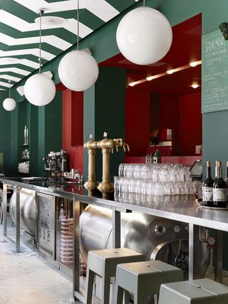 Bar Central in Stockholm stainless steel beer barrels with brass on tap, green walls with red insets