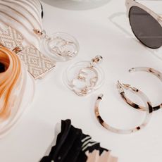 Earrings, sunglasses and scarves on a white table