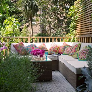 Sitting area with L shaped sofa and colourful cushions and wooden balustrades