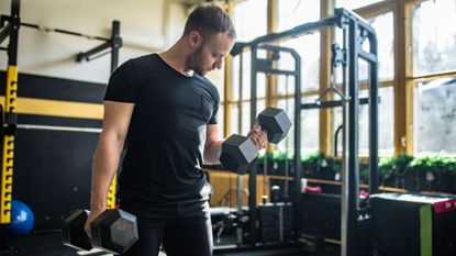 A man doing dumbbell curls in a small gym