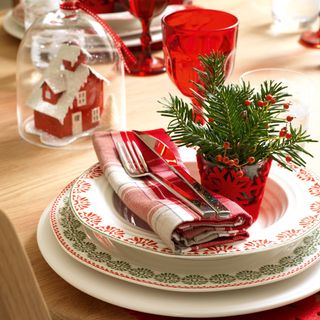 Red scandi christmas place setting with small pine tree and snow globe