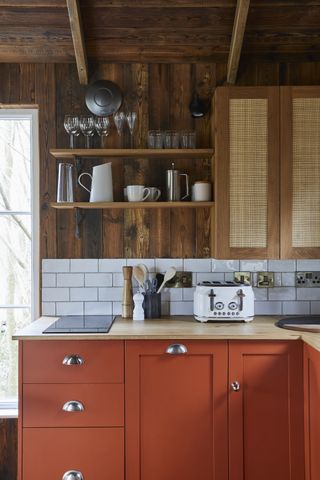 timber panelling above a red kitchen with white worktop