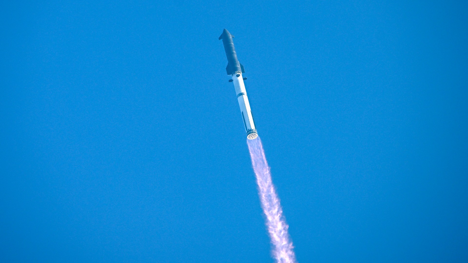 a large silver rocket launches above a plume of fire