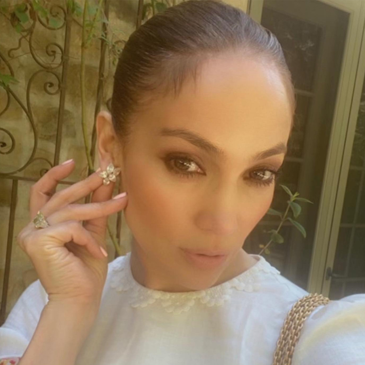 J.lo wears flower diamond earrings and a green diamond engagement ring.