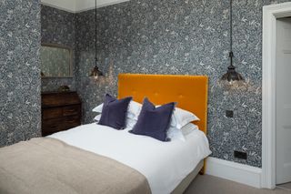 bedroom with blue botanical wallpaper and orange headboard