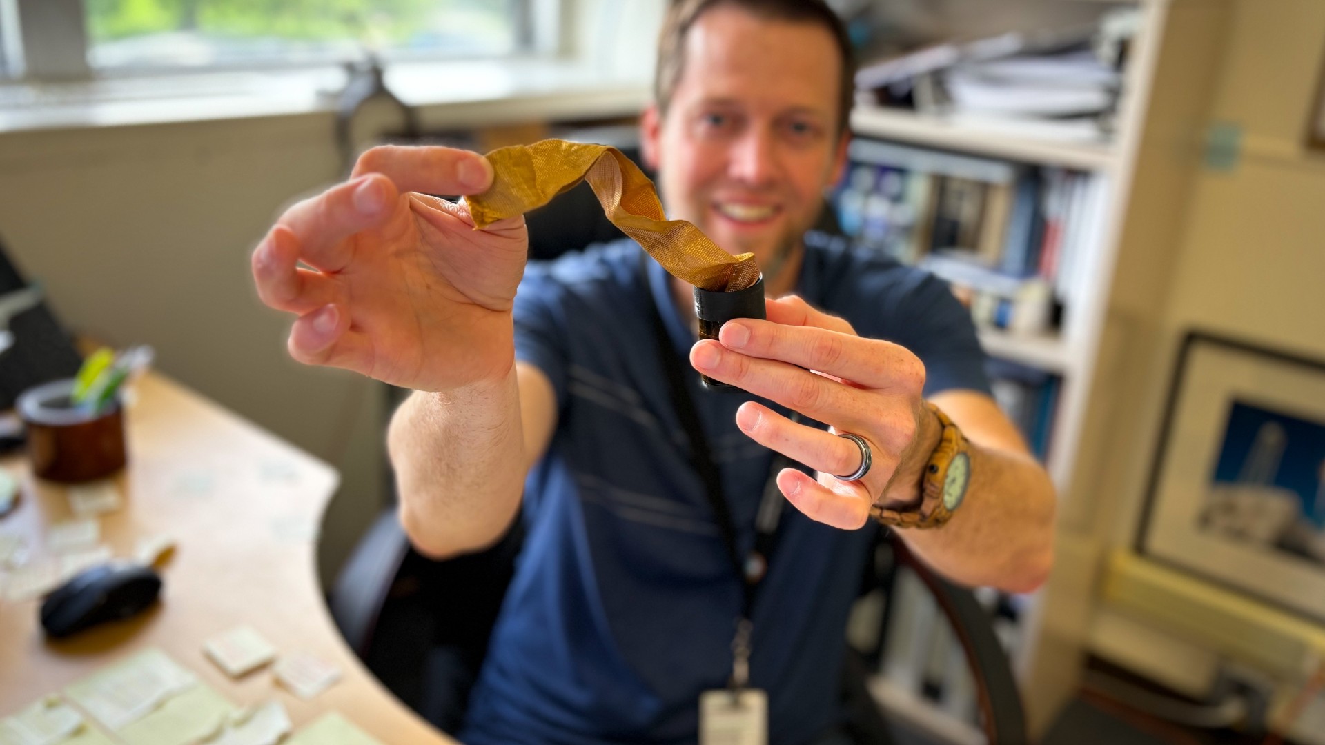 a man in an office holds a crumpled strip of material