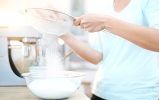 A woman sifting flour into a bowl