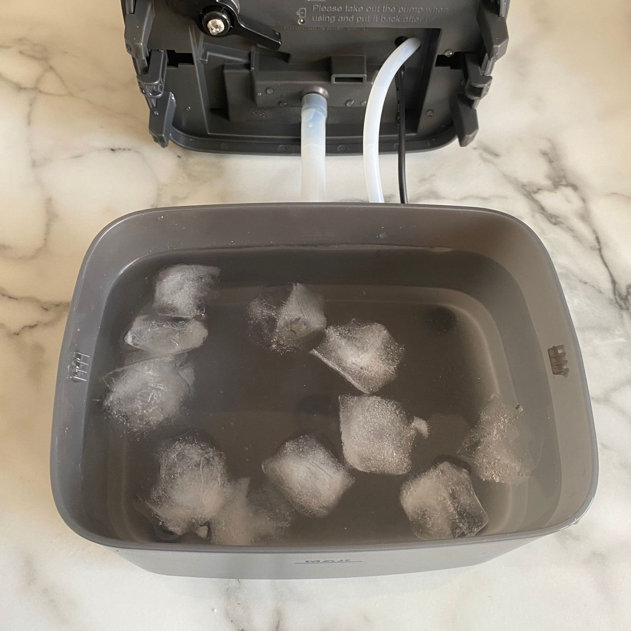 Lower water tank of the Morphy Richards Flexifreeze 1L Air Cooler filled with ice and water, on a marble look kitchen counter