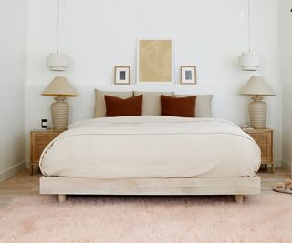 bedroom with large pale wooden platform bed, neutral bedding, matching wooden bedside tables, cream lamps, shades and hanging white shaded pendant lights