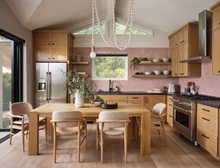 A pink and wood kitchen diner with a draped bare bulb as the statement light