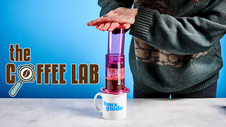 the aeropress clear color in pink in use with the coffee lab logo