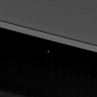 A zoomed-in view of the previous image helps reveal the moon as a faint speck to the left of Earth in this view of our planetary system between the rings of Saturn.