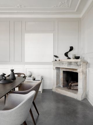 Stone fireplace in the corner of a simple gray dining room