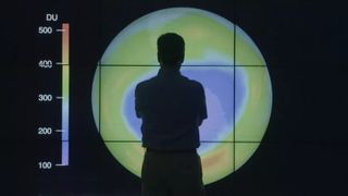 A man standing infront of a projection of the ozone hole