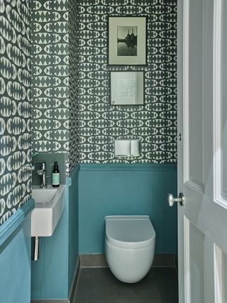 A small bathroom with wood panels and wallpaper