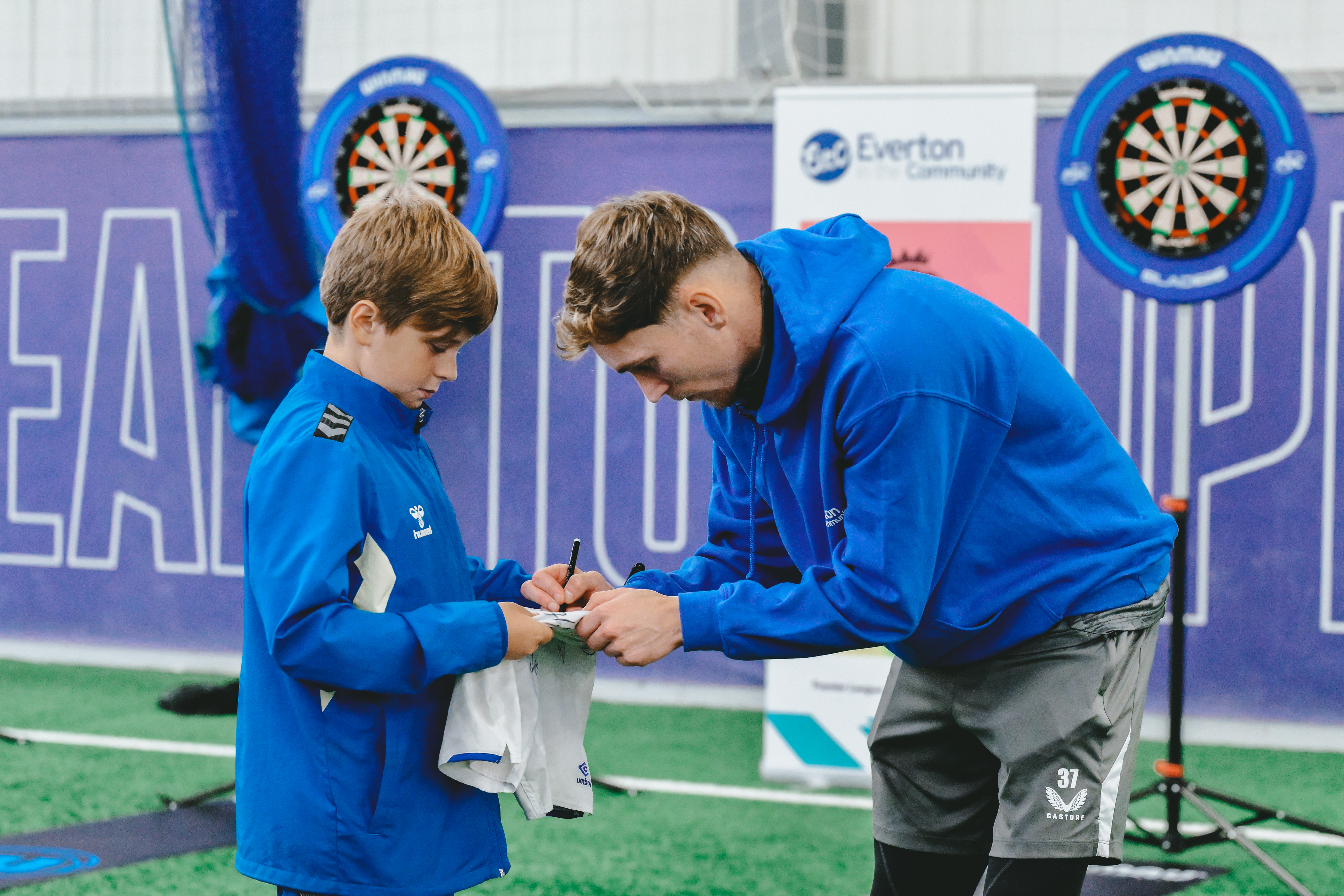 James Garner plays darts with Everton fans at Finch Farm during an Everton in the Community event