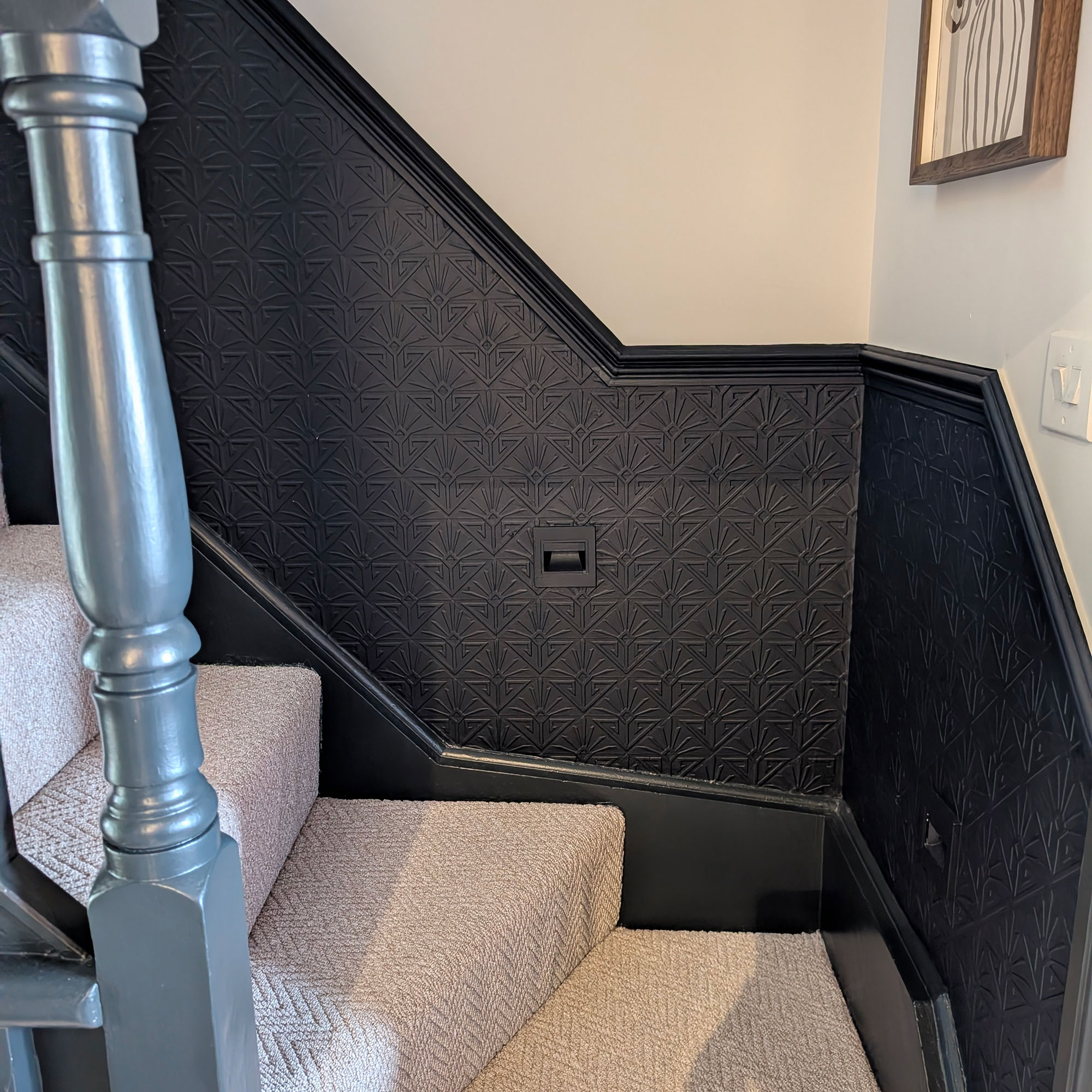 Staircase with banisters and lower half of wall painted in blue-black