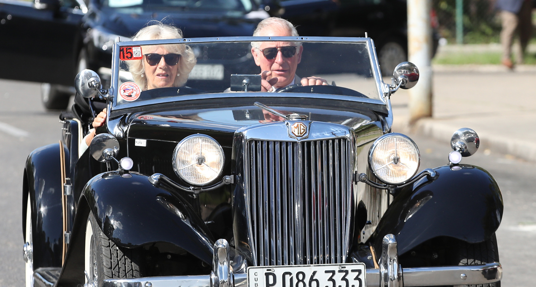 King Charles and Queen Camilla driving in a convertible
