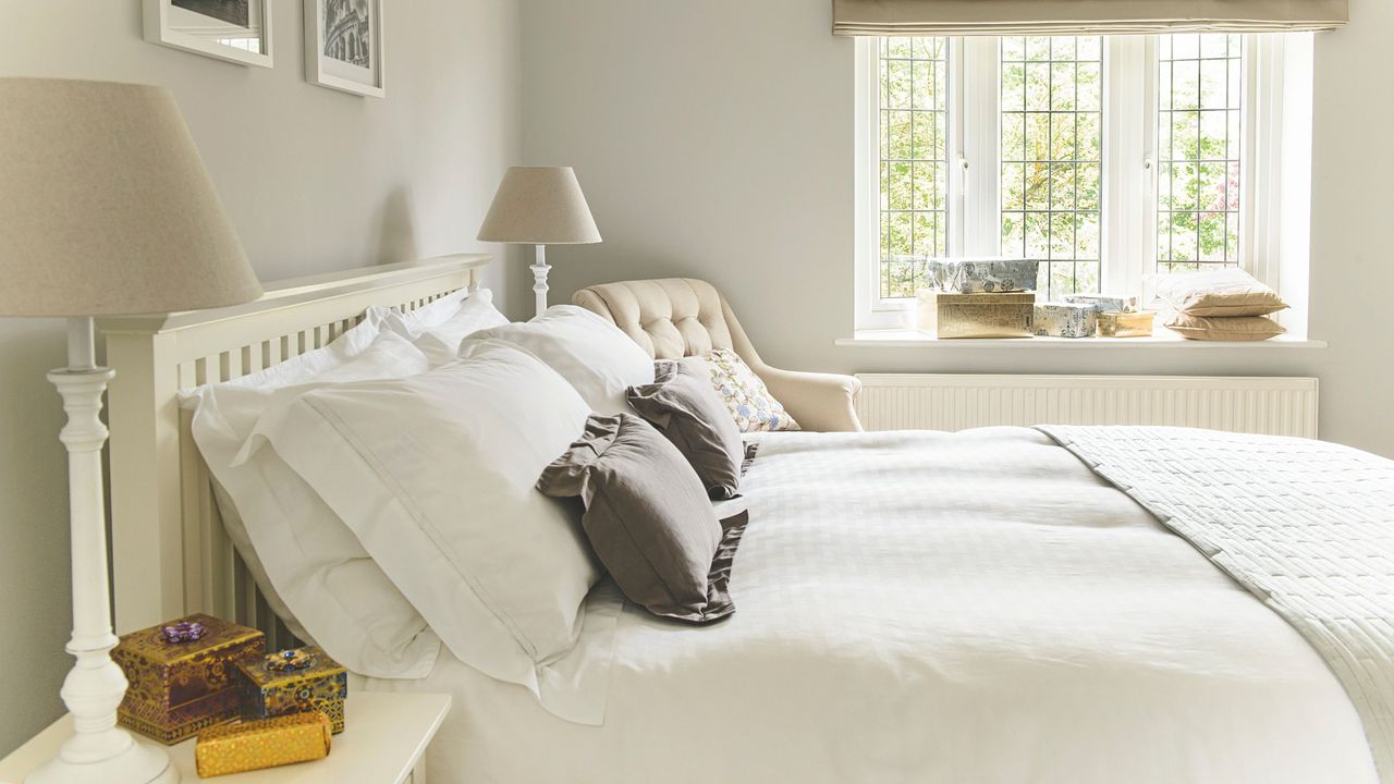 Cream bedroom with cream walls and matching bedding, with a window dead centre