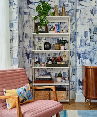 Pink armchair, blue and white wallpaper, white shelves