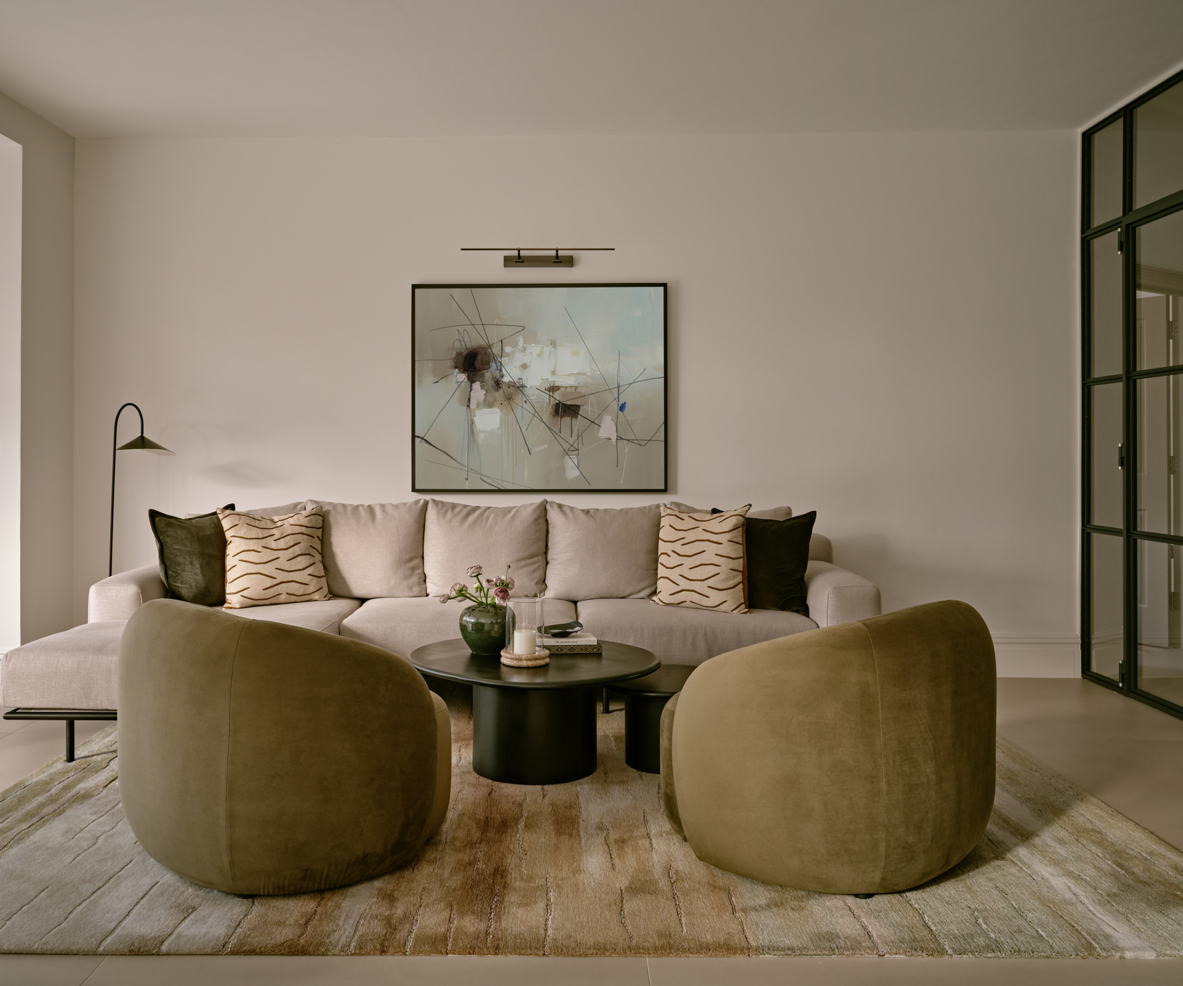 living room with sofa and chairs painted in a light oatmeal colour, a light floor and furniture and furnishings in shades of green and taupe