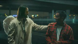 Keanu Reeves and Aziz Ansari looking at each other with Reeve's hand on Ansari's shoulder in Good Fortune.