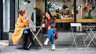 Woman talking to friend on pavement cafe